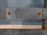 a close up of a metal sign on a bench