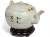 a white tea pot on a wooden stand with chinese writing on it