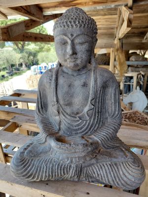 statue représentant une personne assise sur un banc en bois devant un bâtiment