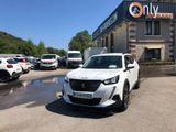 La voiture blanche est garée devant un immeuble sur lequel est accrochée une pancarte.