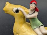 a figurine of a woman riding a yellow horse