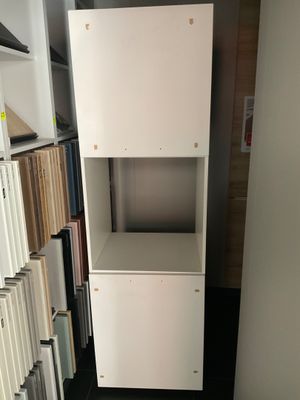 a tall white cabinet with a shelf in the middle of a room