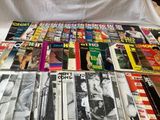 a lot of magazines sitting on a bed with a white sheet
