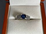 une bague dans une boîte, sertie d'une pierre bleue