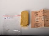 a small piece of gold sitting next to a small piece of paper
