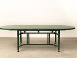 a green table with a metal base and a glass top