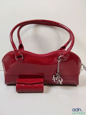 un gros plan sur un sac à main rouge et un portefeuille posés sur une table