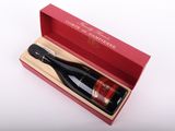 une bouteille de vin dans un coffret rouge posée sur une surface blanche