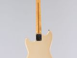 a white electric guitar hanging from a string on a gray background