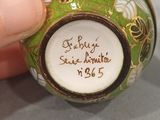 a hand holding a green and white vase with writing on it