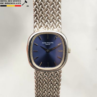 une montre en argent au cadran bleu posée sur une table