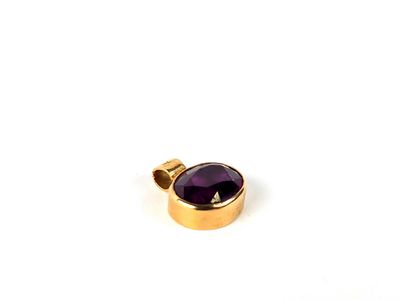 un gros plan d'un pendentif plaqué or orné d'une pierre violette