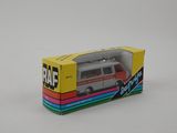 une camionnette miniature qui se trouve dans une boîte posée sur une surface blanche