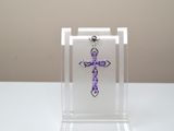 une croix violette posée dans une vitrine transparente posée sur une table