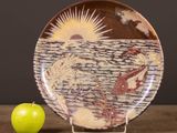 a plate with a painting on it next to a green apple