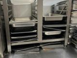 Plusieurs plateaux de nourriture sont empilés sur une étagère métallique dans une cuisine