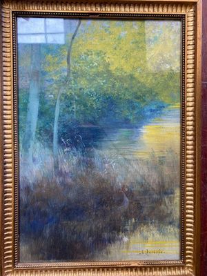 une peinture à l'huile représentant une rivière et des arbres, dans un cadre doré