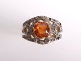 une image représentant une bague ornée d'une pierre orange entourée de diamants