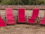 several pink lawn chairs are lined up in a row in a field