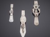 three pieces of silverware on a gray surface with a black background