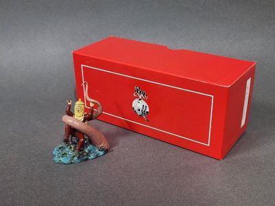 une petite figurine représentant un homme armé d'une épée devant une boîte rouge