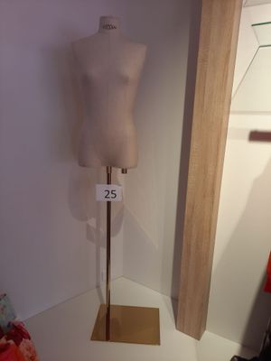 un mannequin assis sur un socle dans une pièce