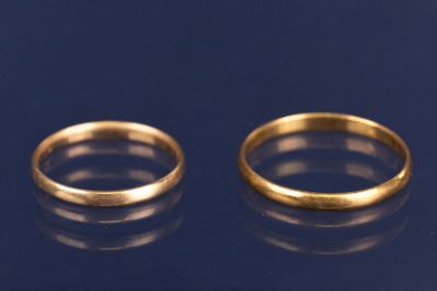 two gold wedding rings on a blue surface