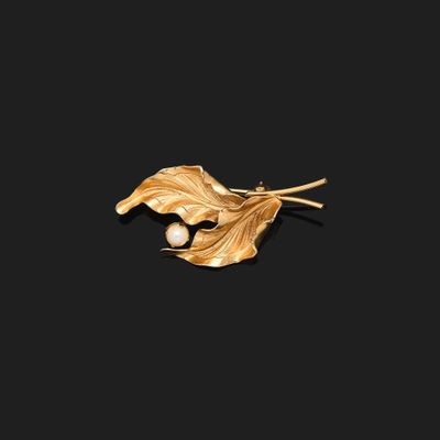 un gros plan sur une broche en feuille d'or ornée d'une perle