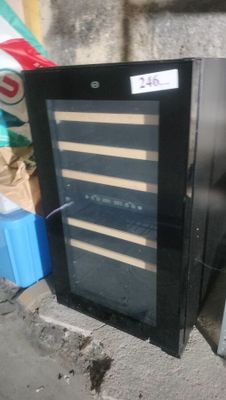 a wine cooler sitting on the sidewalk next to a box of soda