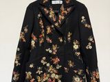 une veste noire ornée de fleurs, suspendue à un cintre