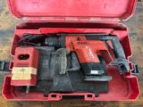 une boîte à outils rouge contenant des outils, posée sur une table en bois