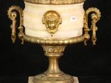 a gold and white urn with a lion head on it