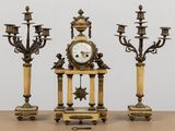 trois bougies et une horloge posées sur une table