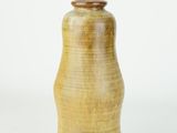 a yellow vase that is sitting on a white surface