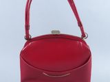 un sac à main rouge muni d'une poignée en métal sur fond blanc