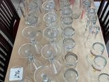 many empty glasses sitting on a table with pictures on the wall behind them