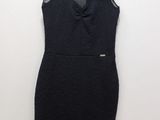 a black dress hanging on a hanger on a white wall