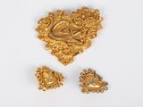 two gold brooches and a pair of earrings on a white surface