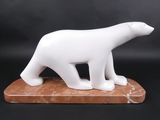 sculpture en marbre représentant un ours polaire, posée sur un socle en marbre, sur fond noir