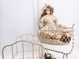 une poupée assise dans un berceau à côté d'un lit