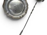 a silver plate and a silver spoon on a white surface