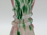 a green and pink vase sitting on a white table