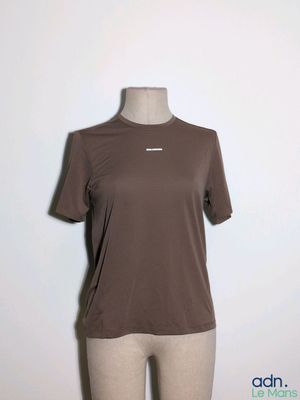 Le t-shirt est marron et porte un logo blanc.