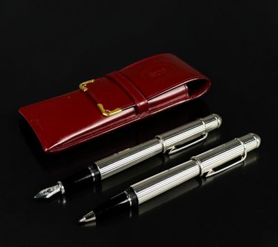 two pens and a red case on a black surface