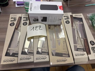 several boxes of knives on a table with a person sitting in front of them