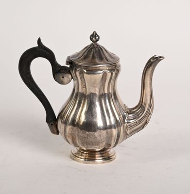 une théière ancienne en argent, dotée d'une anse noire sur un fond blanc