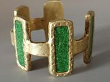 Gros plan sur une bague en or ornée d'une pierre verte