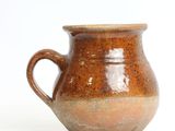 a brown vase that is sitting on a white surface