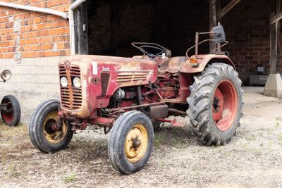 un tracteur rouge garé devant un immeuble