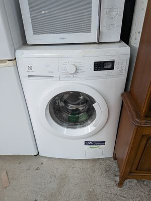 une photo montrant une machine à laver et un micro-ondes dans une pièce